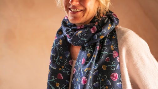 A blue scarf from the AW2024 retail collection is worn